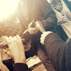 young adult pouring wine enjoying with friends, closeup of the action (square image, vintage effect)