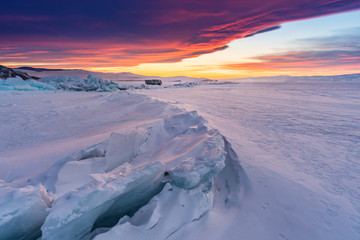 Naklejka na ściany i meble Winter landscape in sunset, Cracked frozen lake covered of snow at lake Baikal in Russia with beautiful sunset sky