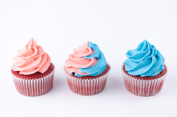 Cupcakes red velvet with blue and pink whipped cream on white background. Picture for a menu or a confectionery catalog.