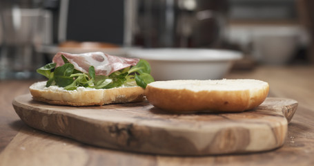 bagel sandwich with coppa and cream cheese on wood board