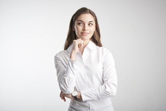 Thinking Young Businesswoman. Portrait Of Young Woman With Hand On His Chin Looking Thoughtful And Thinking Hard While Standing At Isolated White Background. 