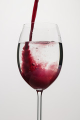 pour purple juice into still water in wine glass