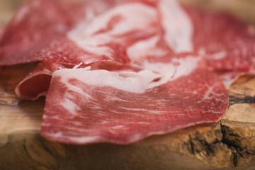 closeup cured italian coppa on olive wood board