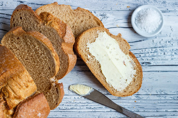 A slice of rye bread with butter on a wooden background is a close-up.