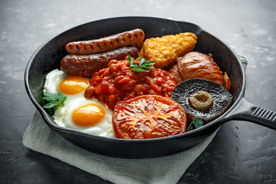 Full English Breakfast With Bacon, Sausage, Fried Egg, Baked Beans, Hash Browns And Mushrooms In Rustic Skillet, Pan.