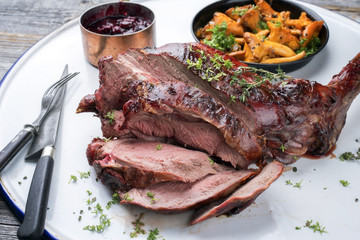 Marinated sliced barbecue aged leg of venison with chanterelles and cherry sauce as top view on...