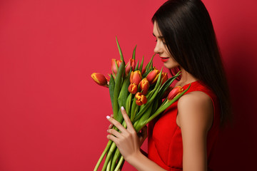 Fototapeta premium Beautiful woman with bouquet of tulip flowers in red dress and looking at the corner with empty text copy space 