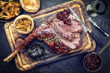 Fotobehang Marinated sliced barbecue aged leg of venison with chanterelles and Yorkshire pudding as top view on a rustic board © HLPhoto