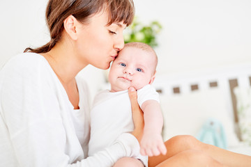 Mutter küsst zärtlich die Stirn von Säugling