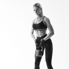 Shot of muscular female bodybuilder doing heavy kettlebell exercise for deltoids Attractive sweaty muscular woman with pony tail hair style and sportswear pumping kettle bell over white background