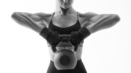 Cropped shot of female bodybuilder in sportswear kettlebells routine on white background Fit and...