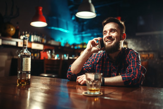 Man sitting at bar counter and talking by phone