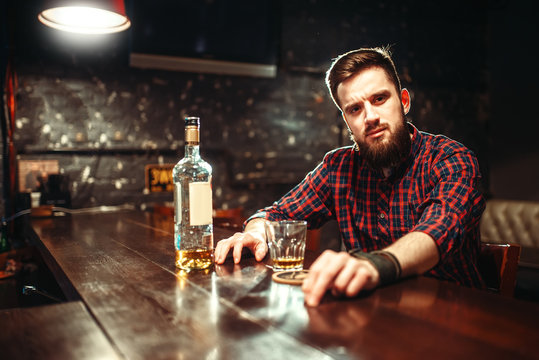 Alcoholic sitting at bar and drinks strong alcohol