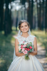 Obraz na płótnie Canvas A beautiful bride portrait in the forest. The stunning young bride is incredibly happy. Wedding day.