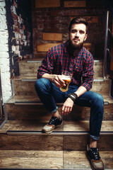 One bearded man sitting on the stairs in bar