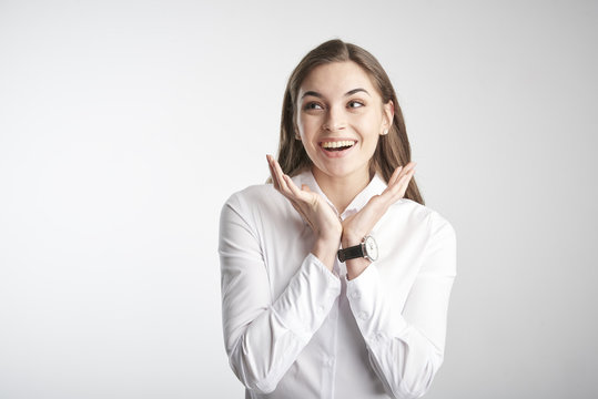 Portrait of happy young businesswoman wearing white shirt while standing with her arms rasied and wondering. Isolated on white background. 