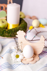 Fototapeta na wymiar egg in a wooden stand with floral elements - elements of the Easter festive table, serving option