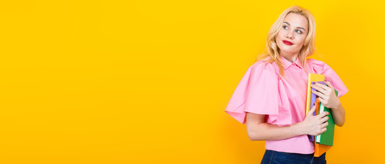 Blonde woman in pink blouse with pile of books