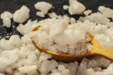 Sea salt on a black decorative antique wooden surface. Background Spa. The concept of the resort....