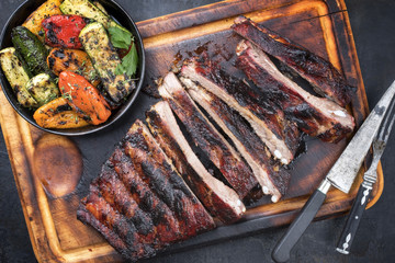 Barbecue spare ribs St Louis cut with hot honey chili marinade sliced as top view on an old rustic board