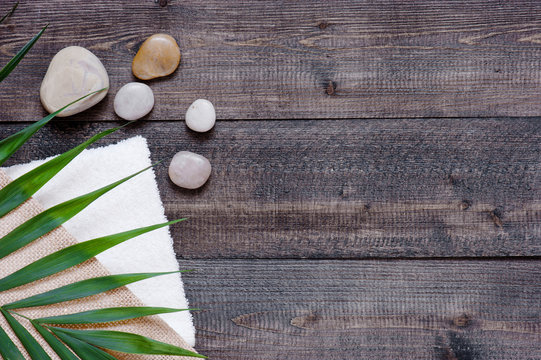 Brown Wooden Background With Terry Towel, Palm Leaf And Stones