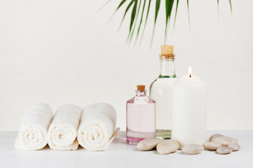 Fototapeta na wymiar Spa delicate composition with burning candle, terry towels, glass bottles and stones