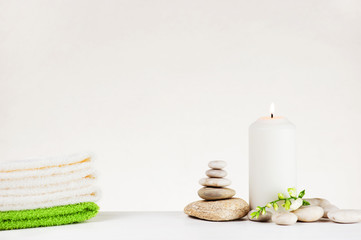 Spa delicate composition with burning candle, stack of towels and stones