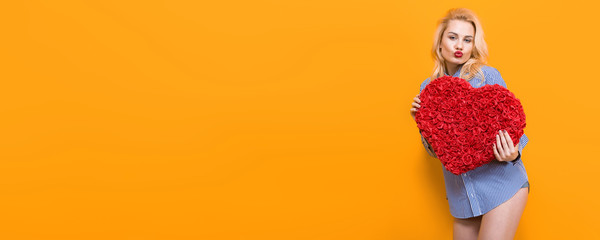 Blonde woman hold big red flower heart. Horizontal