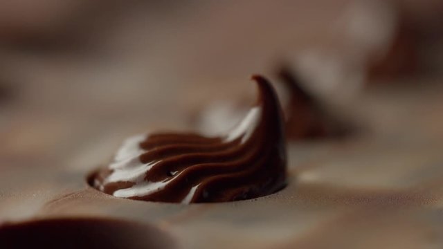 closeup of pastry bag filling candy mold form with chocolate cream. Side view macro
