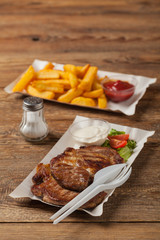 Grilled pork neck served on paper trays.