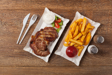 Grilled pork neck served on paper trays.