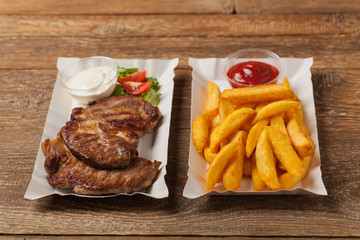 Grilled pork neck served on paper trays.