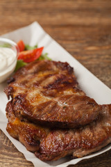 Grilled pork neck served on paper trays.