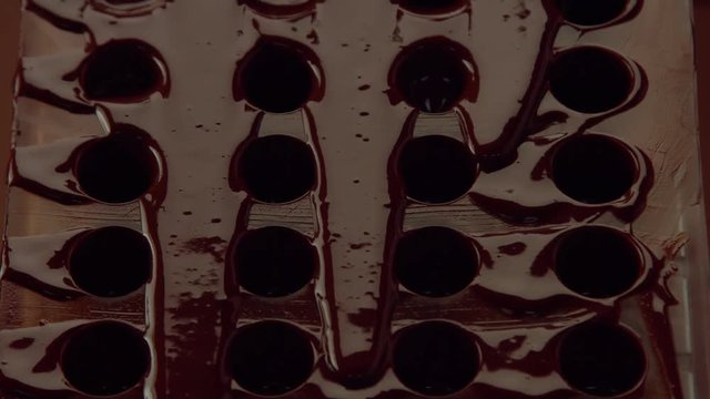 chocolate cand mold form in process of creating candys. liquid chocolate falling down from candy mold