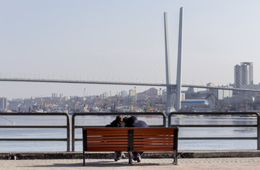 View on Golden Bridge (also known as Zolotoy bridge). The bench with two lovers in the foreground. Russia, Vladivostok.