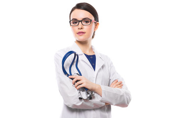 Young woman doctor with crossed arms holding stethoscope in her hand in white uniform on white background