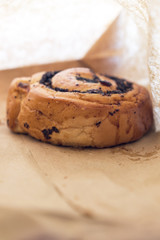 Fresh appetizing bun with poppy seeds in a paper bag.
