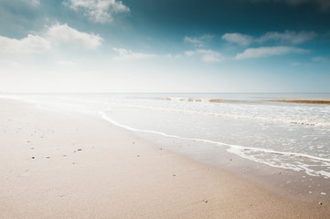 Sandy beach and blue sky with clouds. Coast of the North sea in the Netherlands