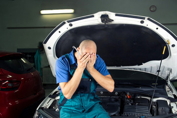 Young car service technician who repair the car engine motor.