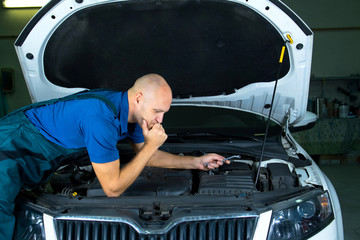 Young car service technician who repair the car engine motor.