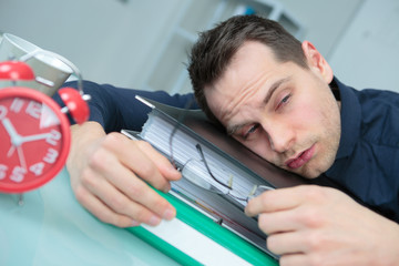 Drowsy man slumped on folders