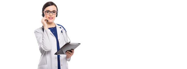Young woman doctor with stethoscope and headphones holding tablet in her hands in white uniform on white background