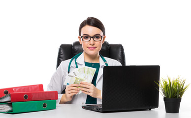 Young woman doctor with stethoscope sitting on the desk at medical office in white uniform on white background