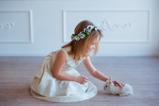 Cute little girl playing with bunny. Spring and easter portrait of beautiful child with rabbit.