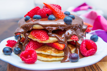 dish with pancakes and strawberry,raspberry and blueberry and chocolate 