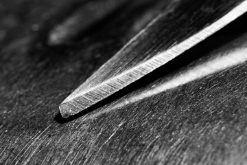Grunge black and white background with a knife on a metal surface macro