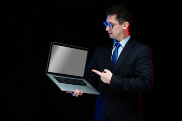 Portrait of confident handsome stylish businessman holding laptop in his hands on black background