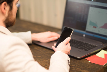 Business person checking stocks on laptop and phone