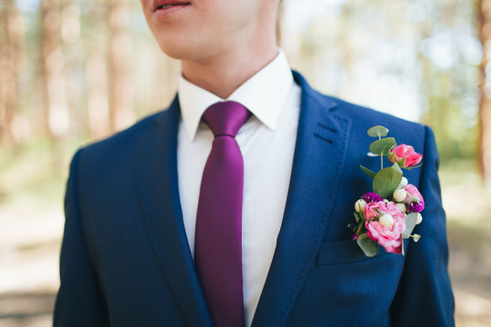 Groom's boutonniere of pink and red roses on a blue suit