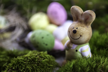 Easter holiday concept with cute handmade eggs, bunny, chicks and party hats in bowl on wooden table